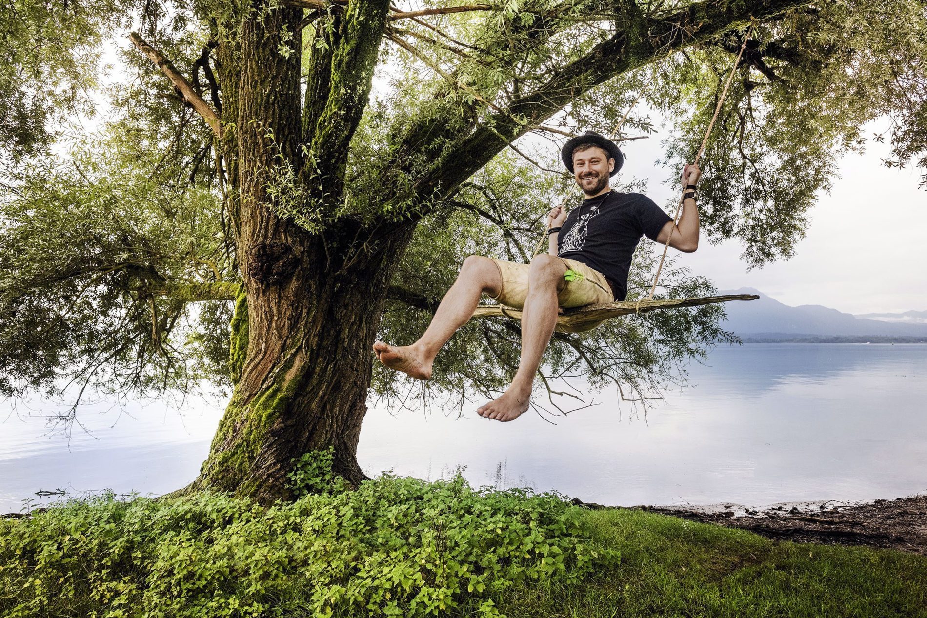 Florian Blickenberger am Chiemsee Florian Blickenberger schaukelt. Die Schaukel hängt an einem großen Baum, der an einem großen See steht.