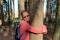 Frau umarmt achtsam einen Baum im Wald
