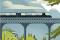 Die Illustration zeigt einen Zug, der über eine Brücke fährt. Im Hintergrund sieht man Berge.
