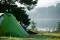 Camping am See: Ein Mann sitzt vor seinem Zelt an einem See.