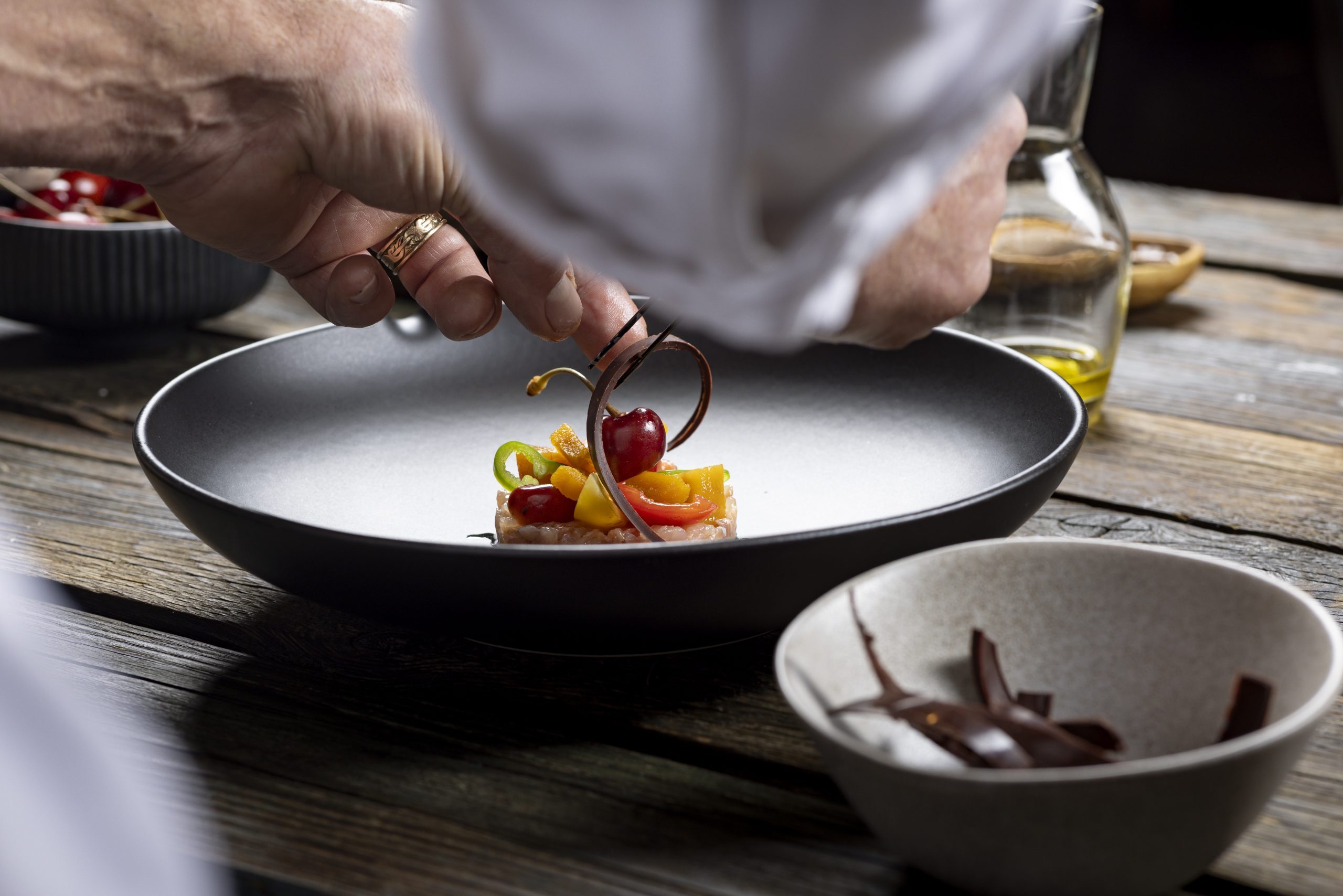 Huchen-Tartar mit Kaffee-Creme und Salz-Kirschen auf dunklem Teller