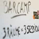 Flipchart mit Aufschrift "Barcamp, 3 Räume = 3 Sessions"