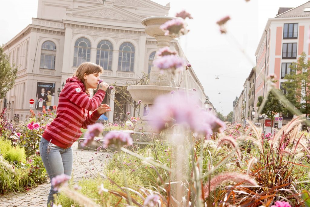 Frau mit eingeschränktem Sehvermögen riecht an einer Blume.