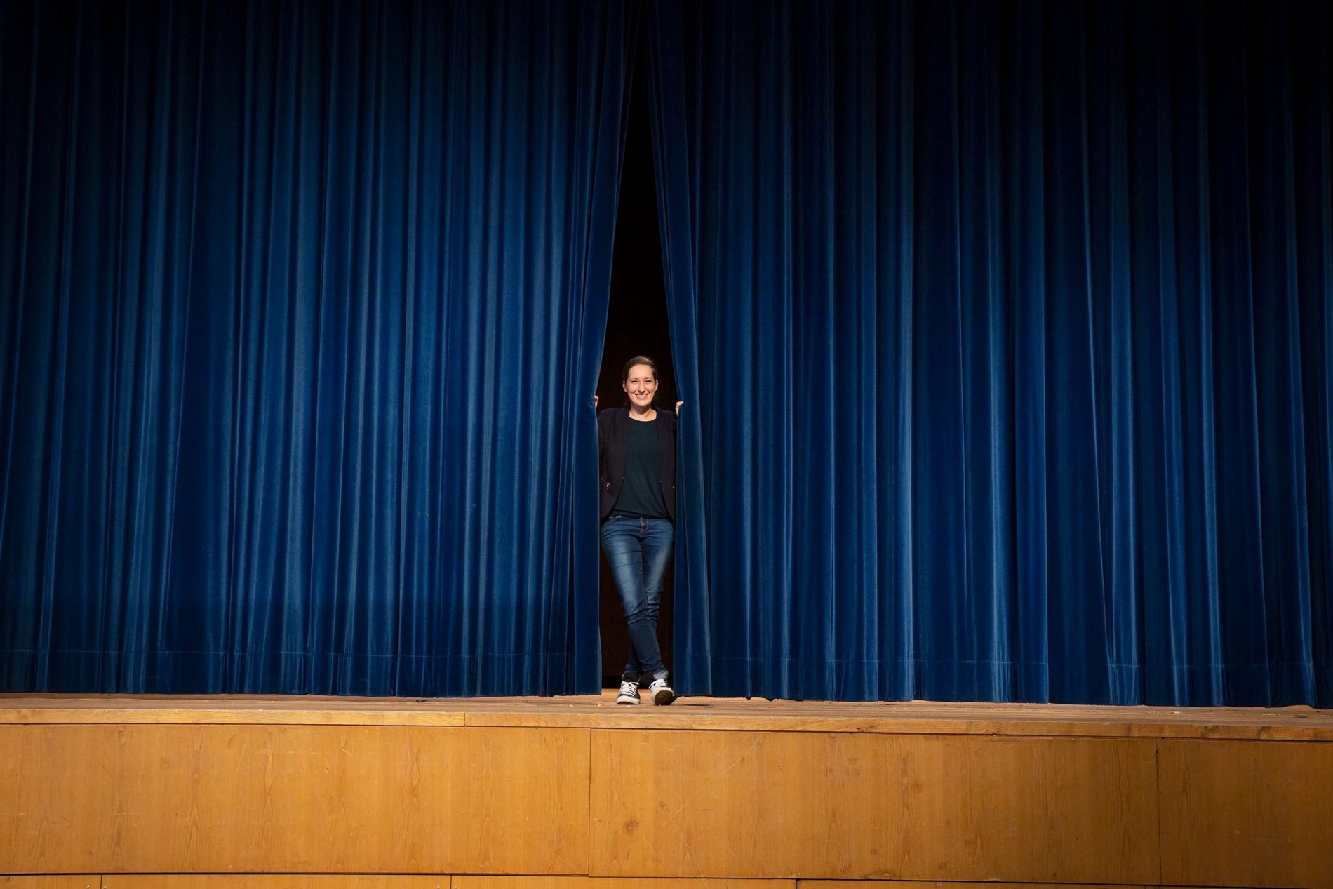 Magdalena Stuber, Eventmanagerin bei der AIB-Kur GmbH in Bad Aibling, steht auf der Bühne und schaut durch den Vorhang.