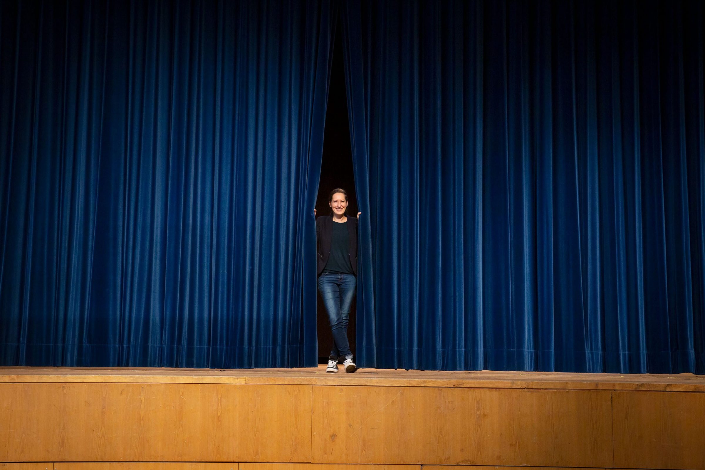 Magdalena Stuber, Eventmanagerin bei der AIB-Kur GmbH in Bad Aibling, steht auf der B&uuml;hne und schaut durch den Vorhang.