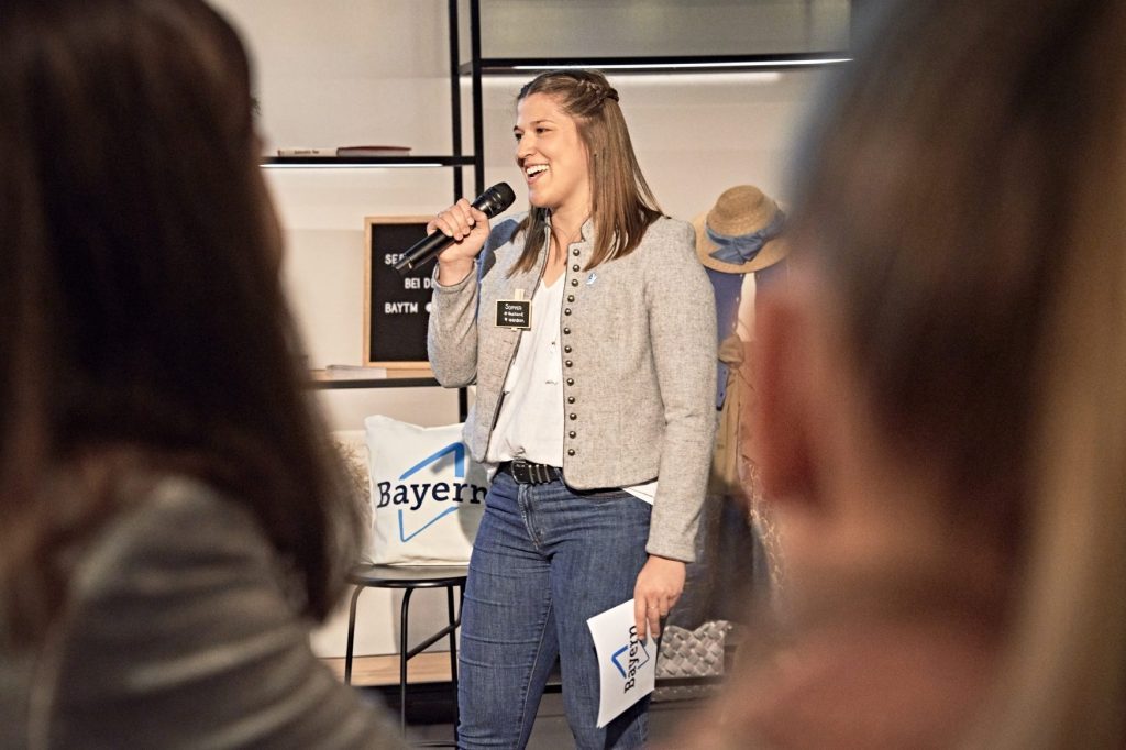 Sophia Buckl mit einem Mikrofon in der Hand bei der Moderation von "Tourism Next - Bayerns junges Netzwerk"