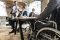 Flexibilität und New Work: Ein Geschäftsmann, der in einem Rollstuhl sitzt, ist bei einem Meeting mit weiteren Personen im Büro.