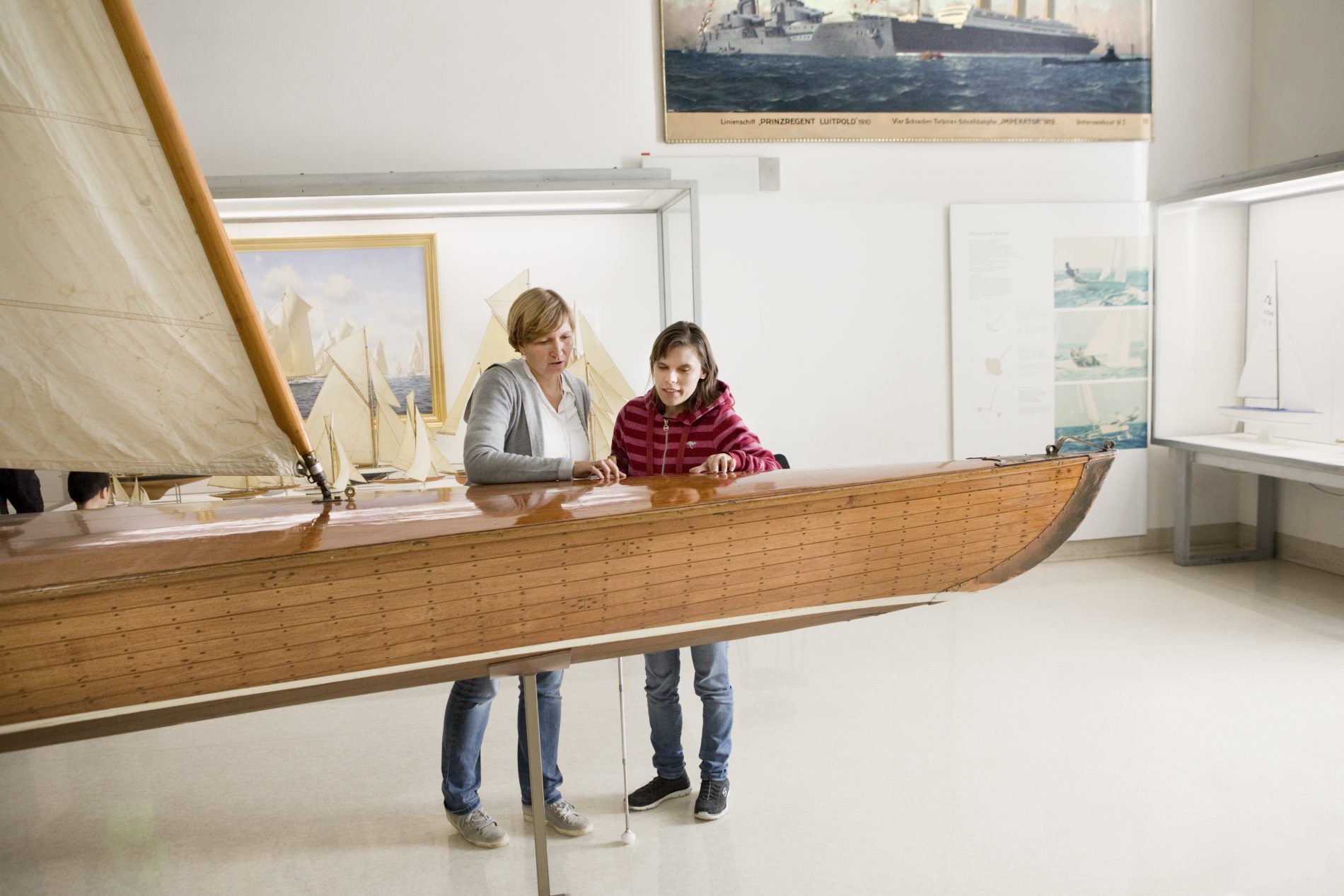 Barrierefrei_Muenchen_33 2 Frauen stehen hinter einem Segelboot in einem Museum.