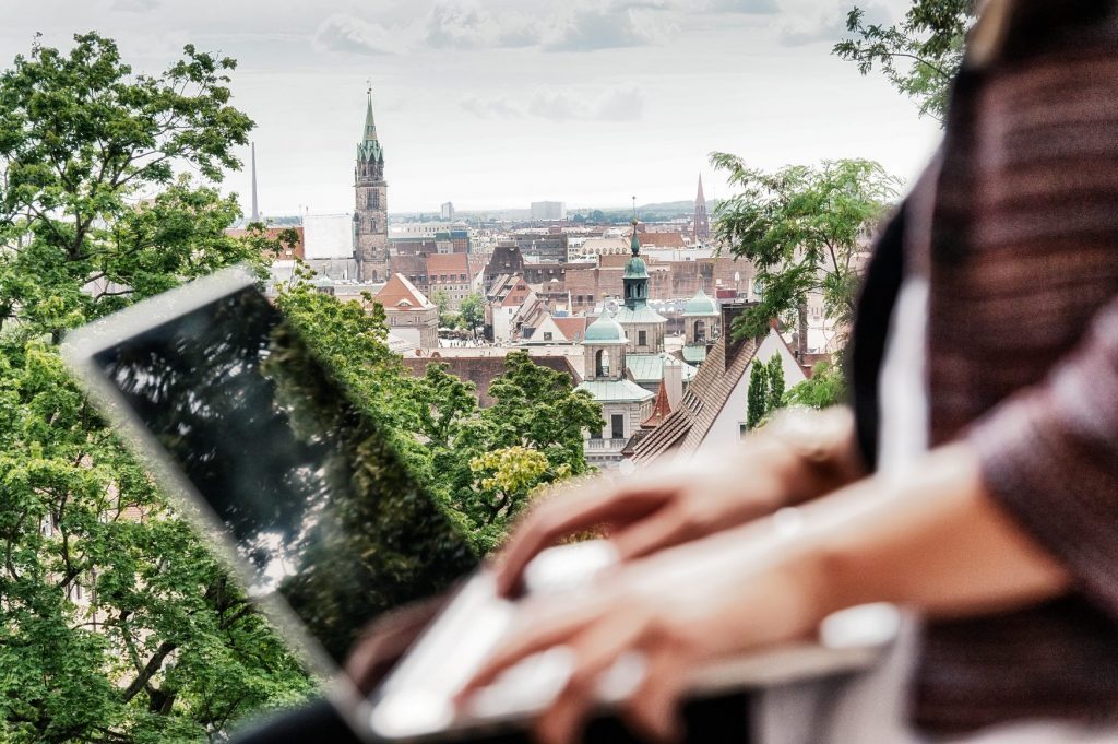 Eine Person sitzt an ihrem geöffneten Laptop, im Hintergrund ist Nürnberg zu sehen.