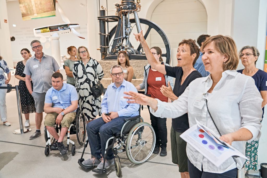 Gruppe von Menschen - teilweise im Rollstuhl - in einem Museum