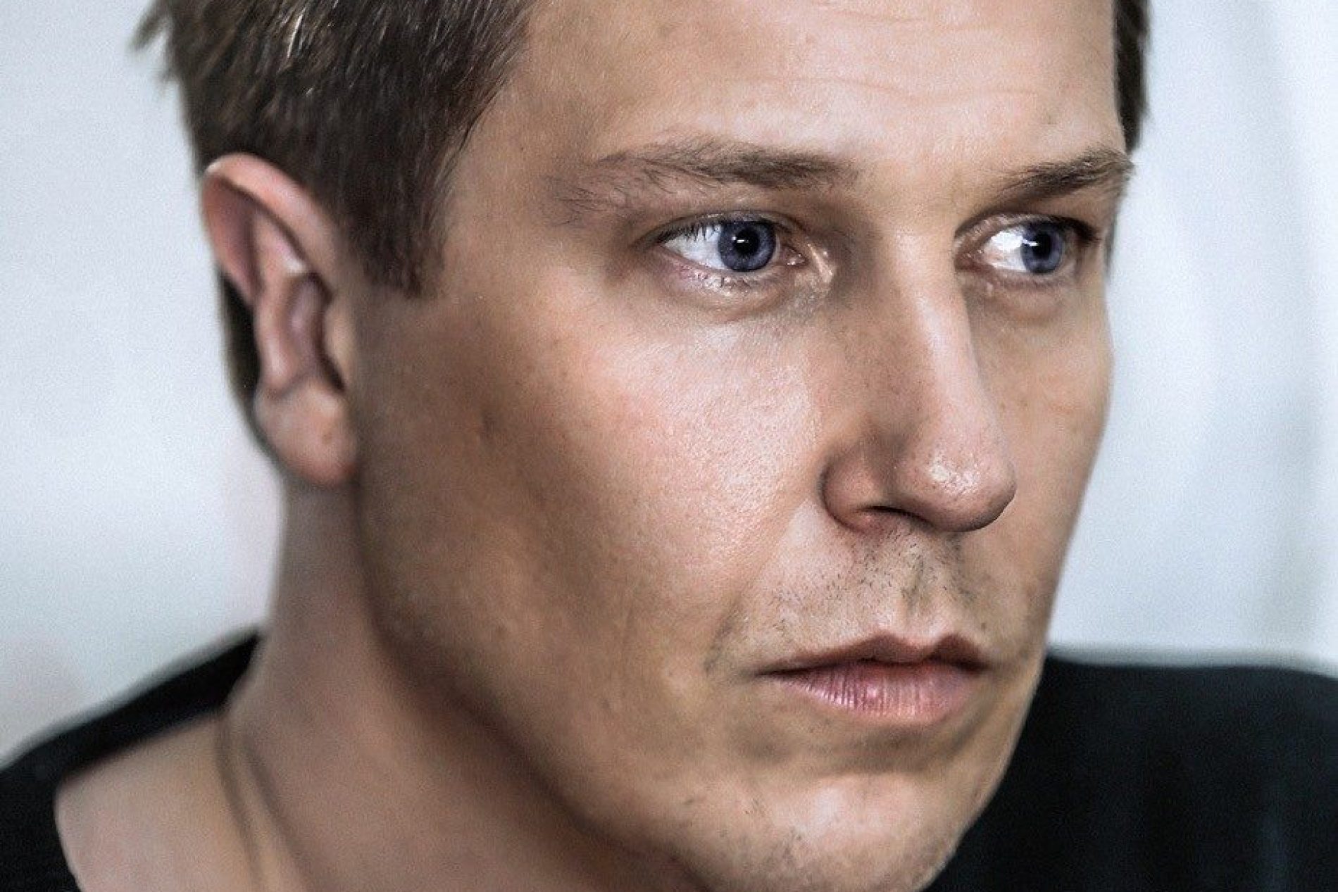 guido-schmelich Porträt von Guido Schmelich: Mann mit dunklem Haar, schwarzem Pullover, seitlich nach rechts blickend.