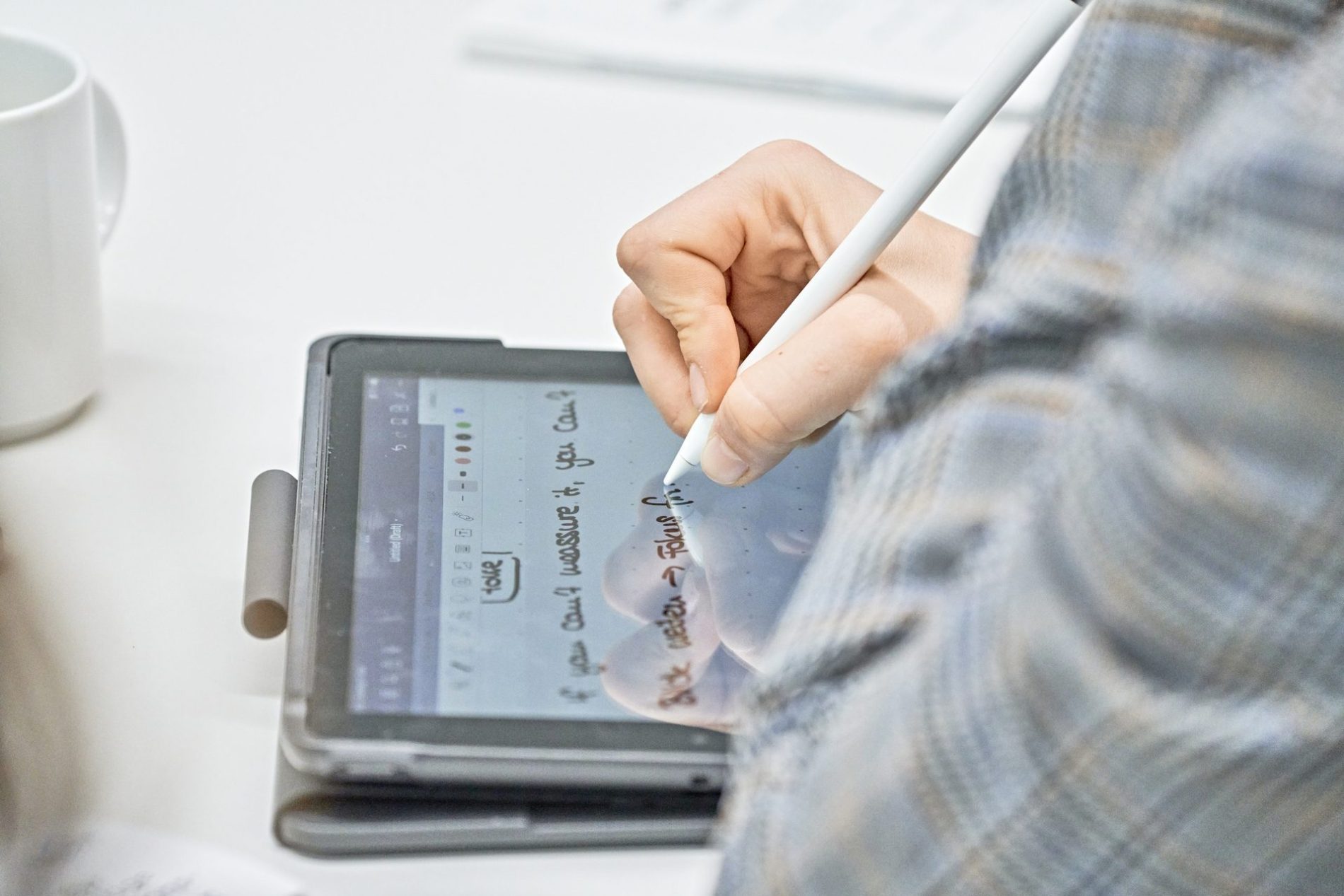 MICE Nachhaltigkeitsworkshop, Munich Urban Collab Hand mit Stylus schreibt auf Tablet, digitale Notizen sichtbar; MICE Nachhaltigkeitsworkshop, Digitalisierung von Arbeitsprozessen.
