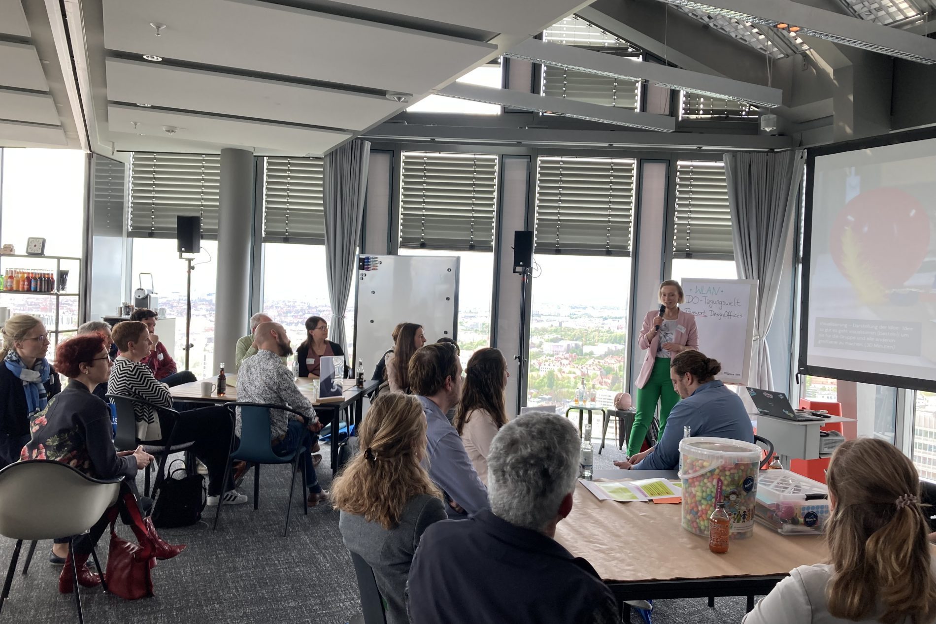 Moderation Thinkathon durch Catharina Fischer (Realizing Progress) Moderatorin Catharina Fischer moderiert Thinkathon vor Gruppe in Konferenzraum; Beamer, Whiteboard, Fensterblick.