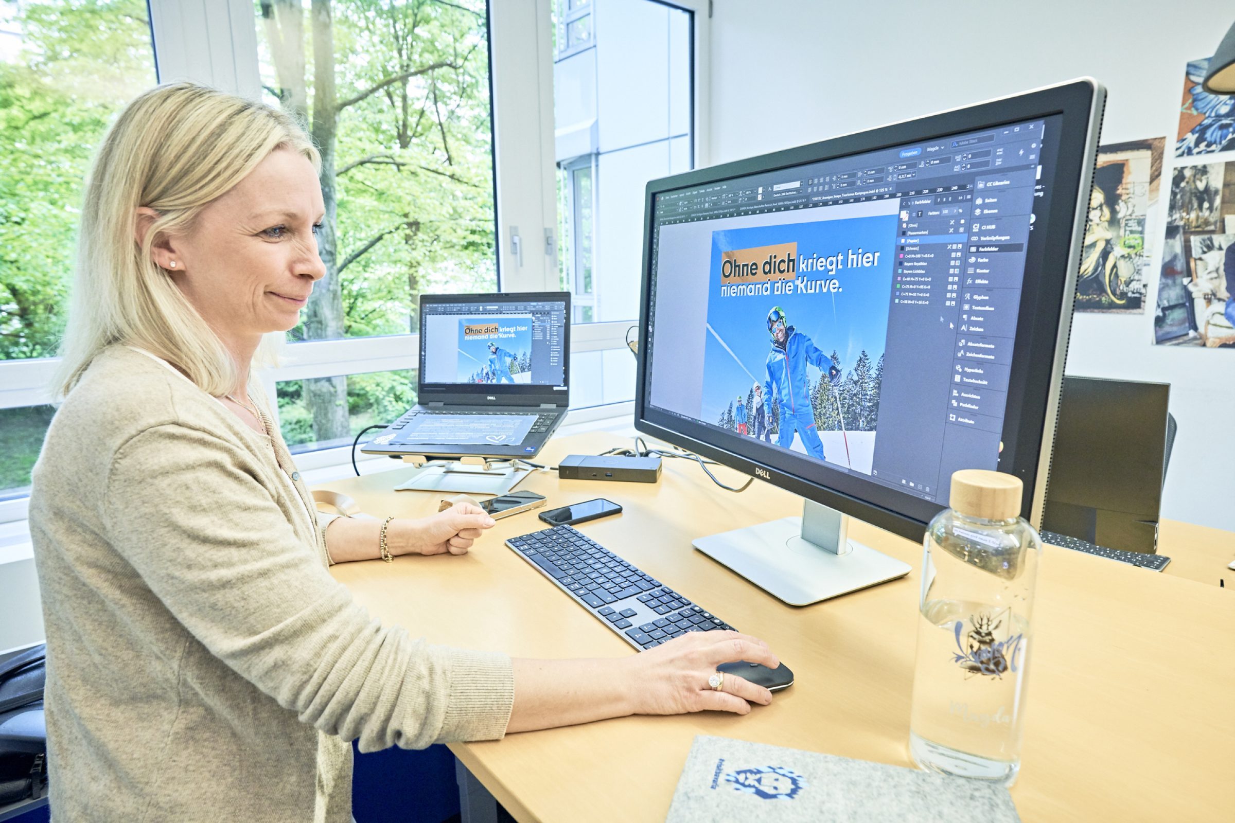 Frau arbeitet am Computerbildschirm mit Werbegrafik und dem Satz Ohne dich kriegt hier niemand die Kurve; B&uuml;roumgebung.