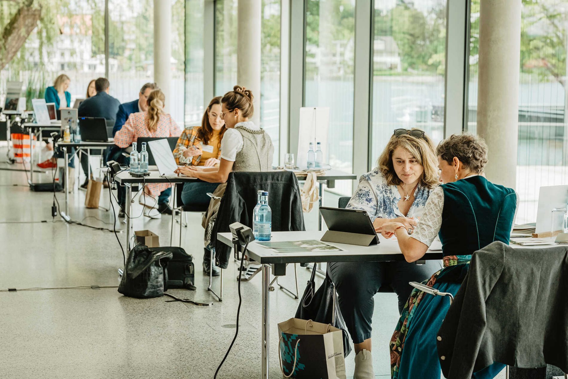 Deutschland, Bayern, Allgäu, Lindau, Bavaria Workshop 2024 Teilnehmerinnen arbeiten an Laptops und Tablets in einem hellen Konferenzraum während des Bavaria Workshop 2024 im Allgäu.