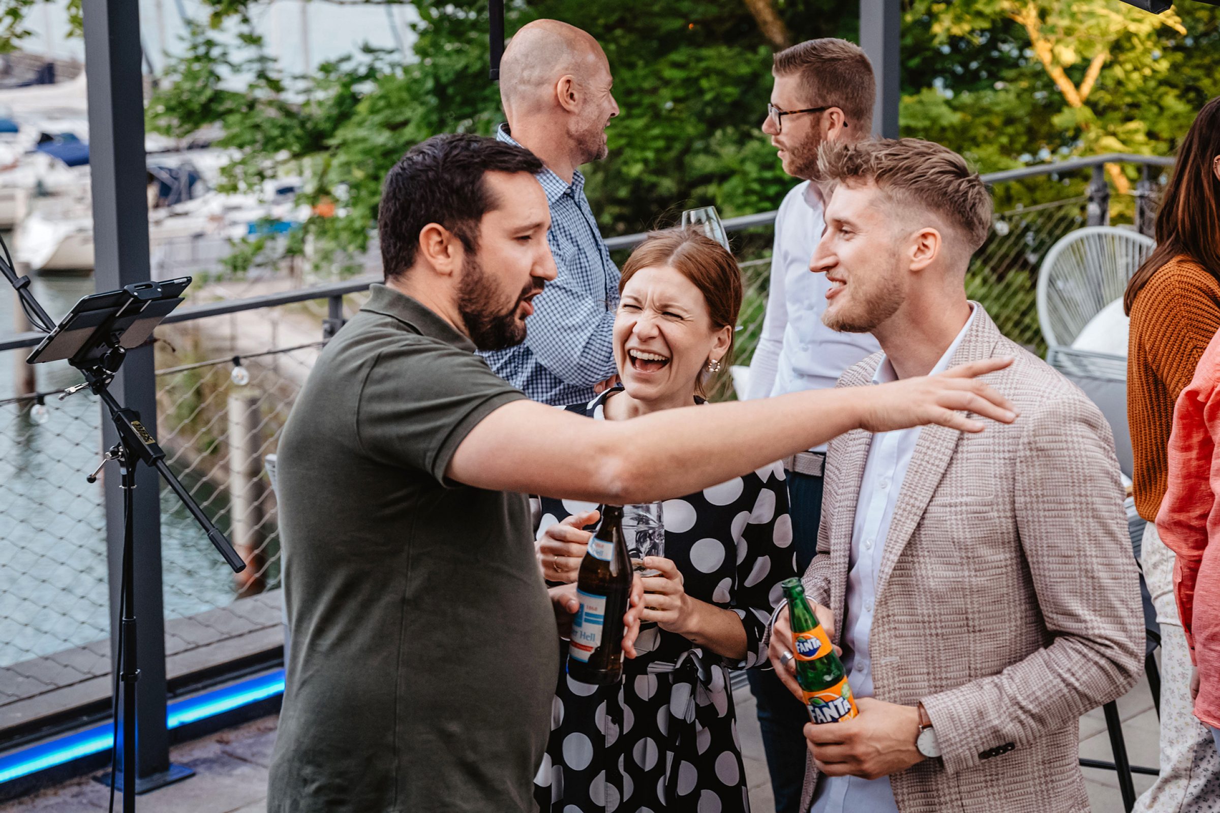 Gruppe feiernder Menschen auf Dachterrasse beim Bavaria Workshop, Getr&auml;nke in der Hand, Marina im Hintergrund