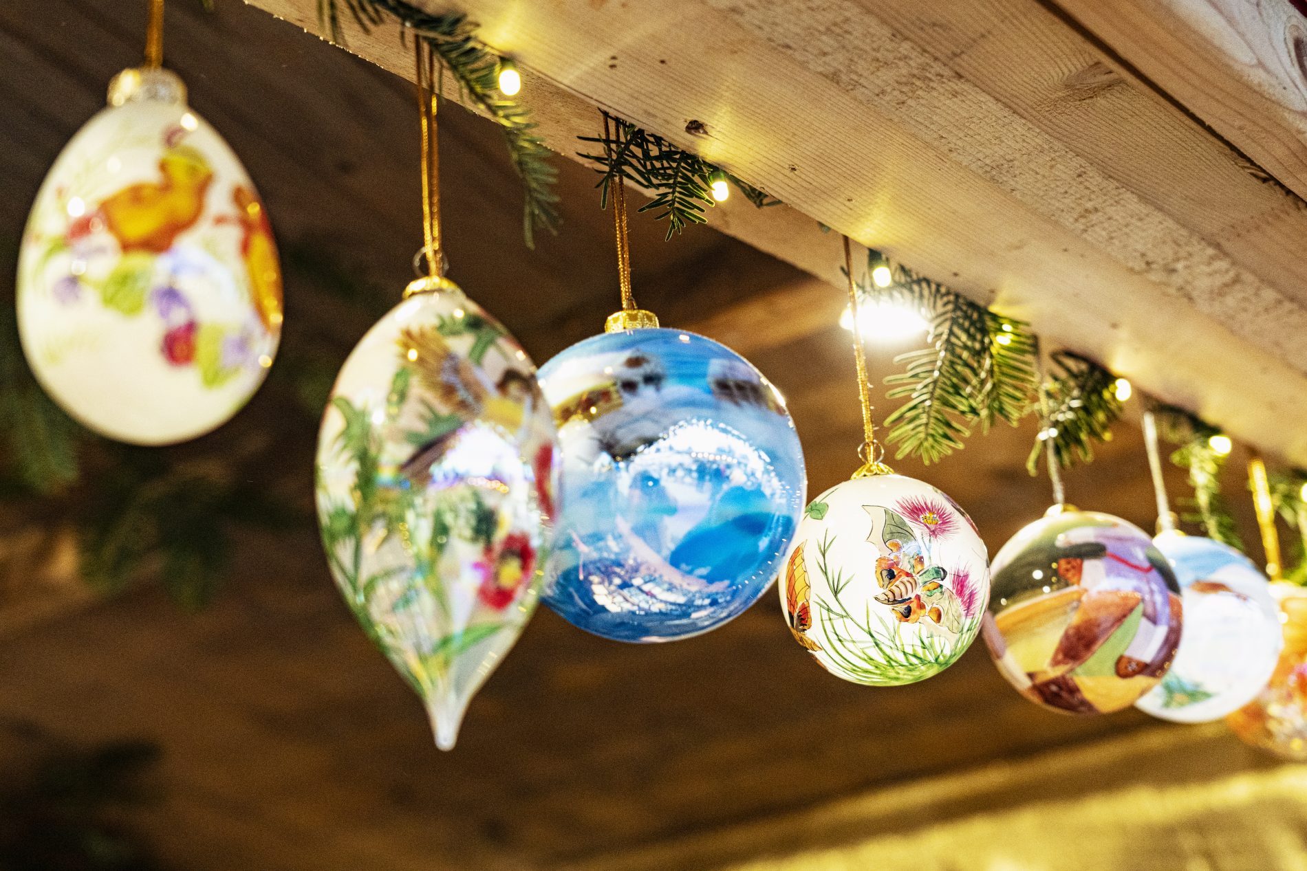 Hängende Glas-Weihnachtskugeln mit bunten Motiven, Lichterkette, Holzbalken – Weihnachtsmarkt Fraueninsel, Oberbayern