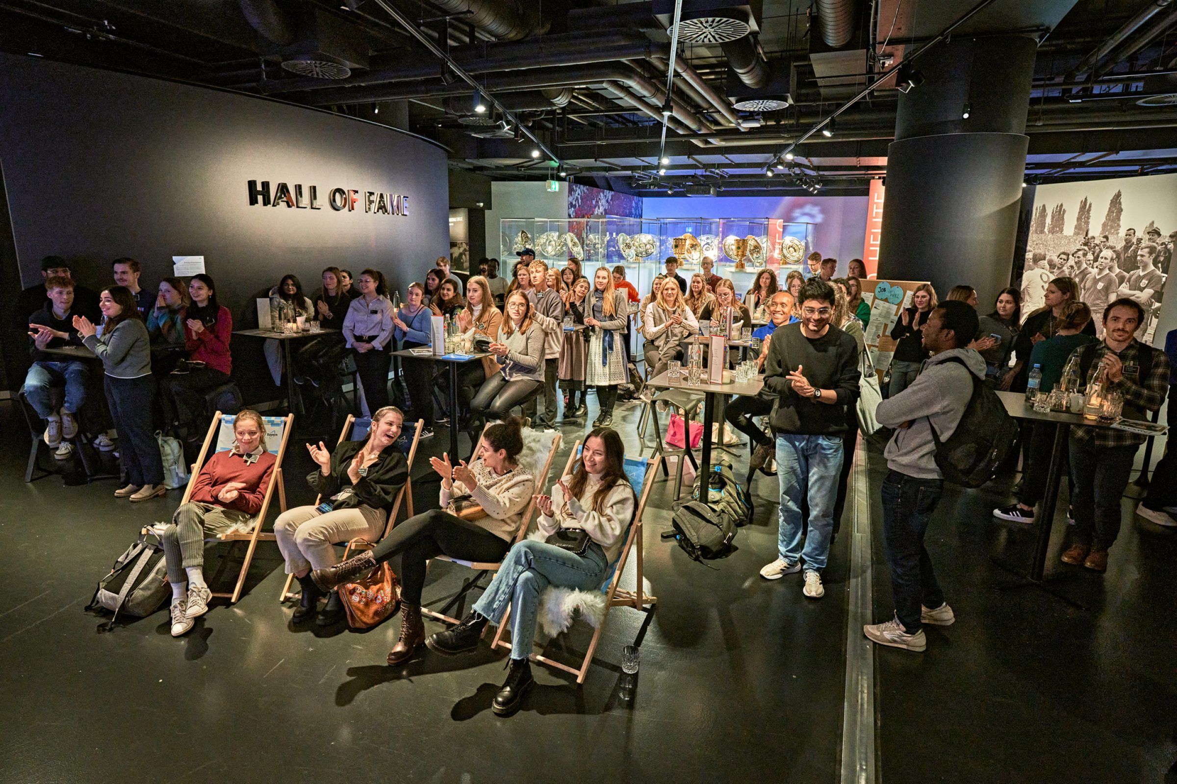 Gruppe applaudiert in Ausstellungsraum vor Hall of Fame; viele Besucher versammelt beim Tourism Next Event.