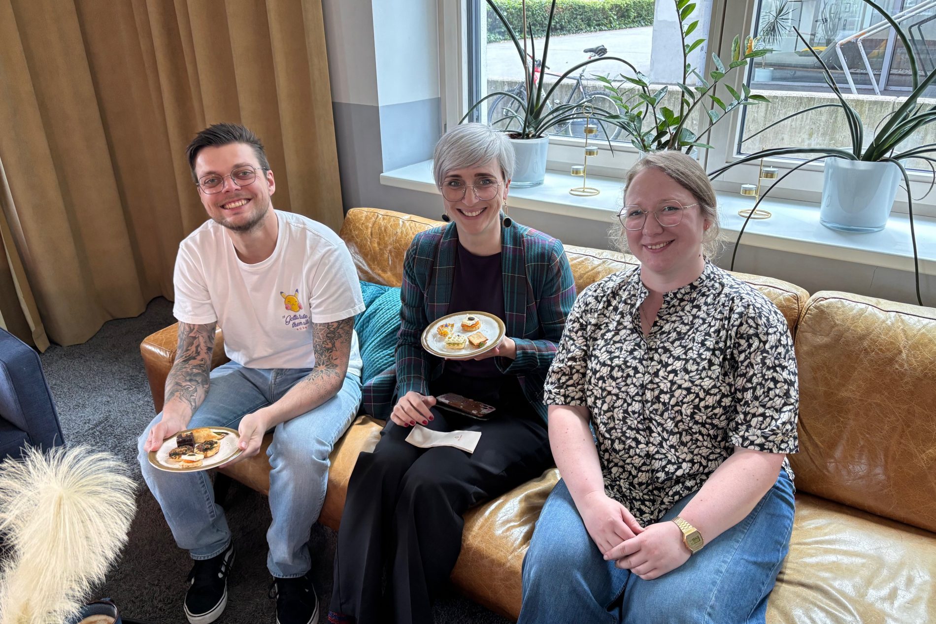 Drei Personen sitzen auf einem Ledersofa während einer Kaffeepause beim ODTA Treffen Innsbruck 2025, essen Gebäck.