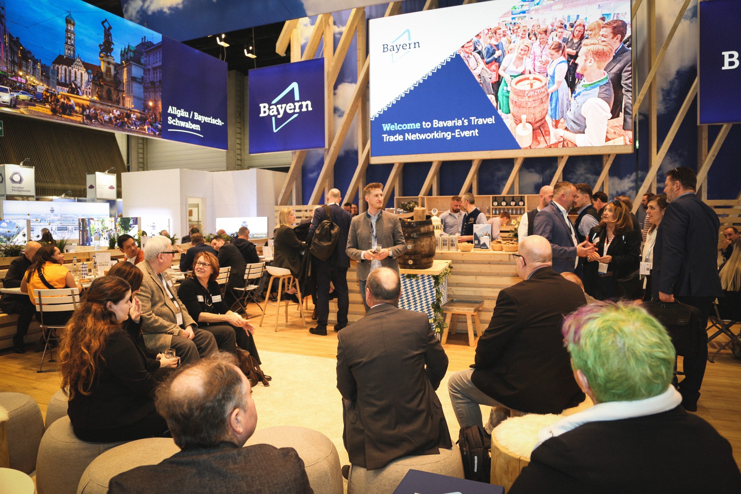 Bayern-Stand auf der ITB Berlin 2025: Besucher versammeln sich am Barbereich vor Holzkonstruktion und Banner Bayern.