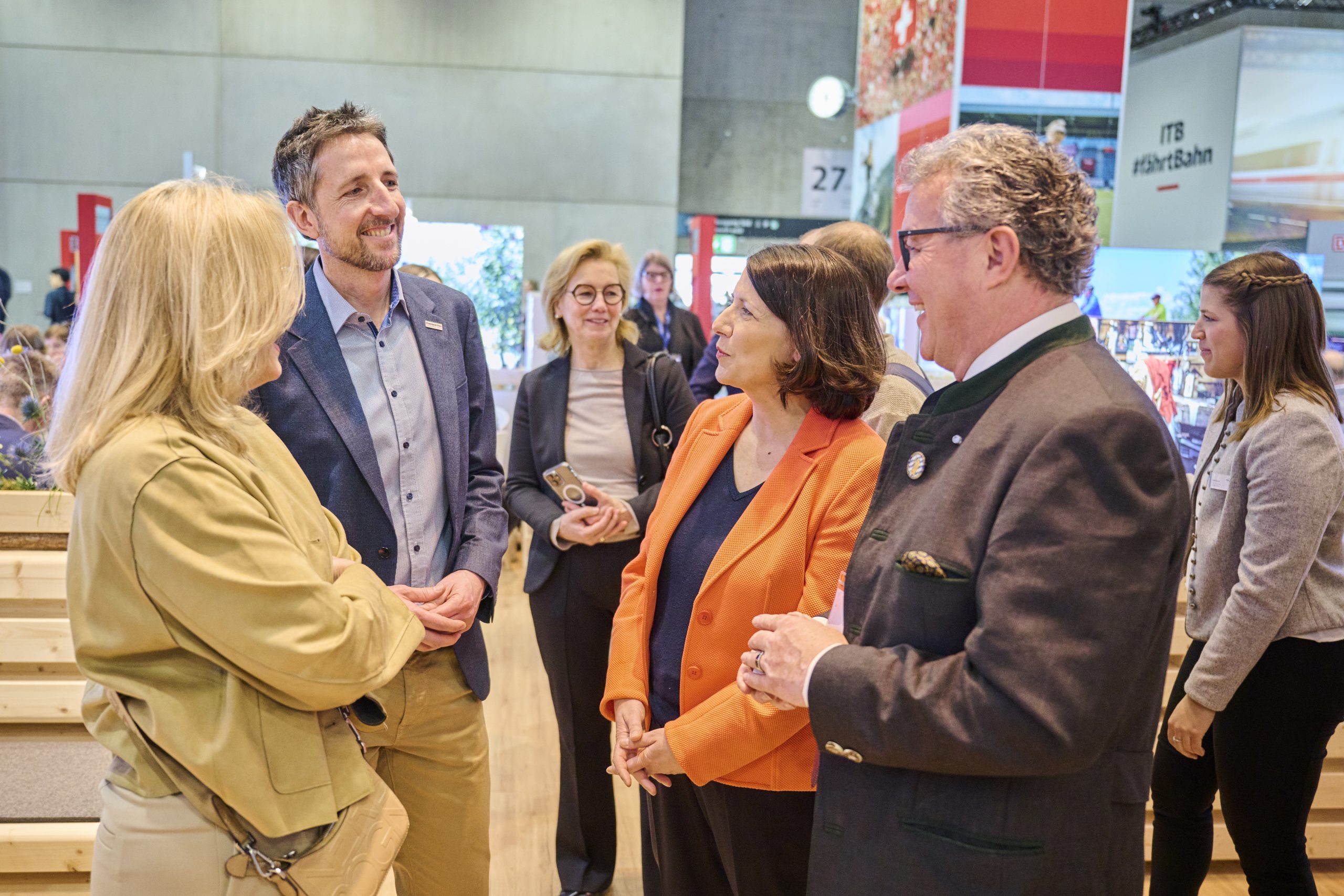 Gruppe von sechs Personen im Gespr&auml;ch am Bayern-Stand auf der ITB Berlin 2025.