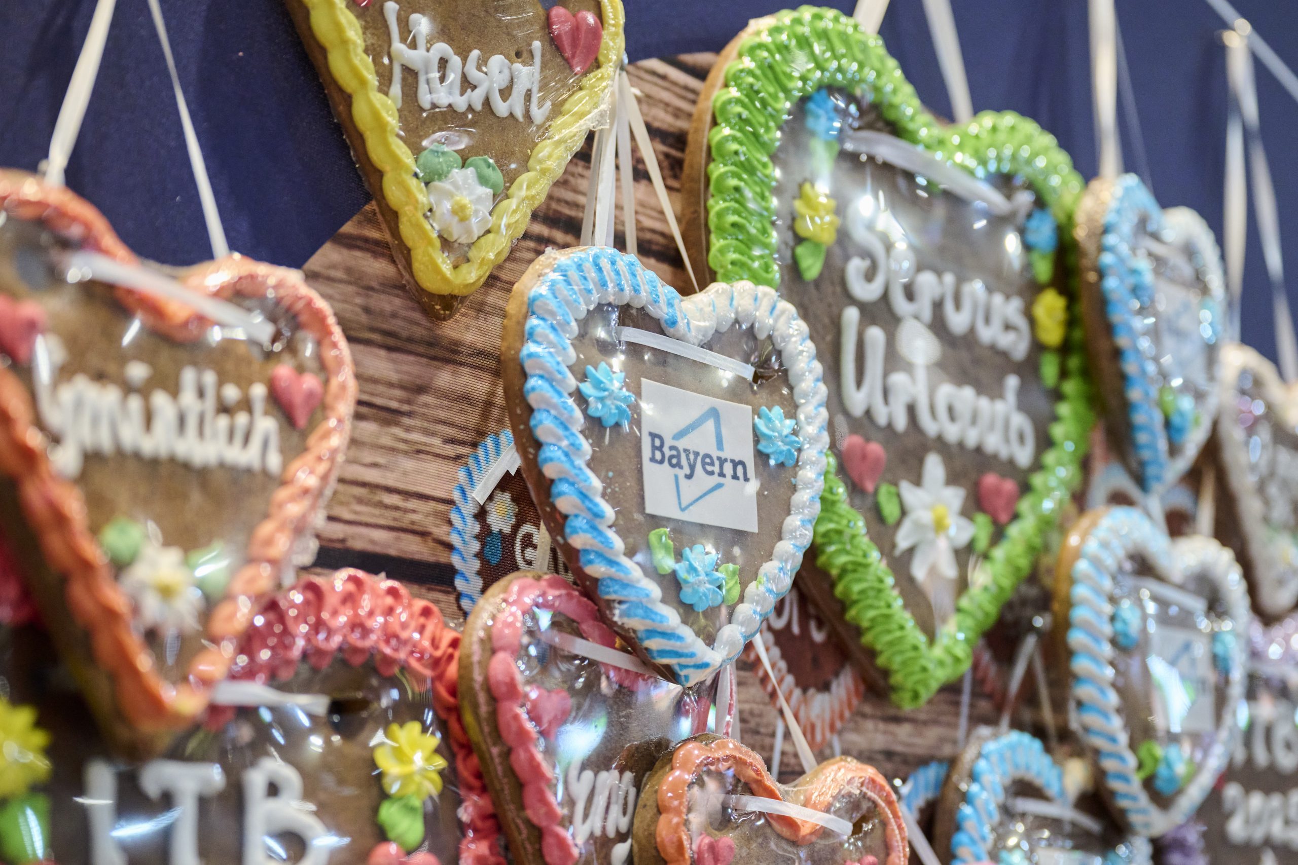 Bunte Lebkuchenherzen mit Zuckerguss h&auml;ngen am Bayern-Stand bei der ITB Berlin 2026, sichtbar Bayern-Logo.