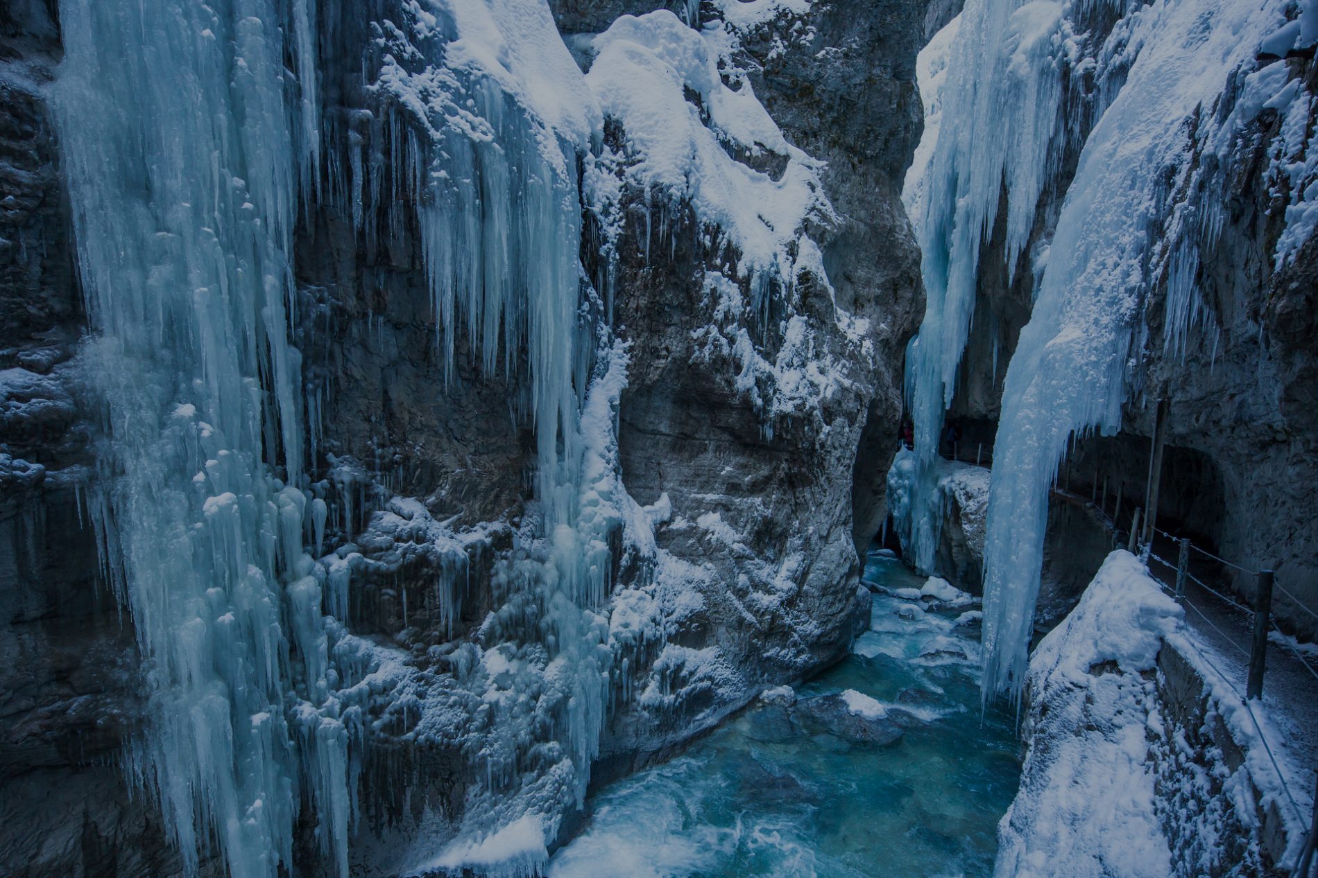 0142_Partnachklamm_Winter-(c)-erlebe.bayern—Bernhard-Huber Winterliche Eiswand in der Partnachklamm; Eiszapfen, frostiger Fels, gefrorenes Wasserbecken, schneebedeckte Felswände.