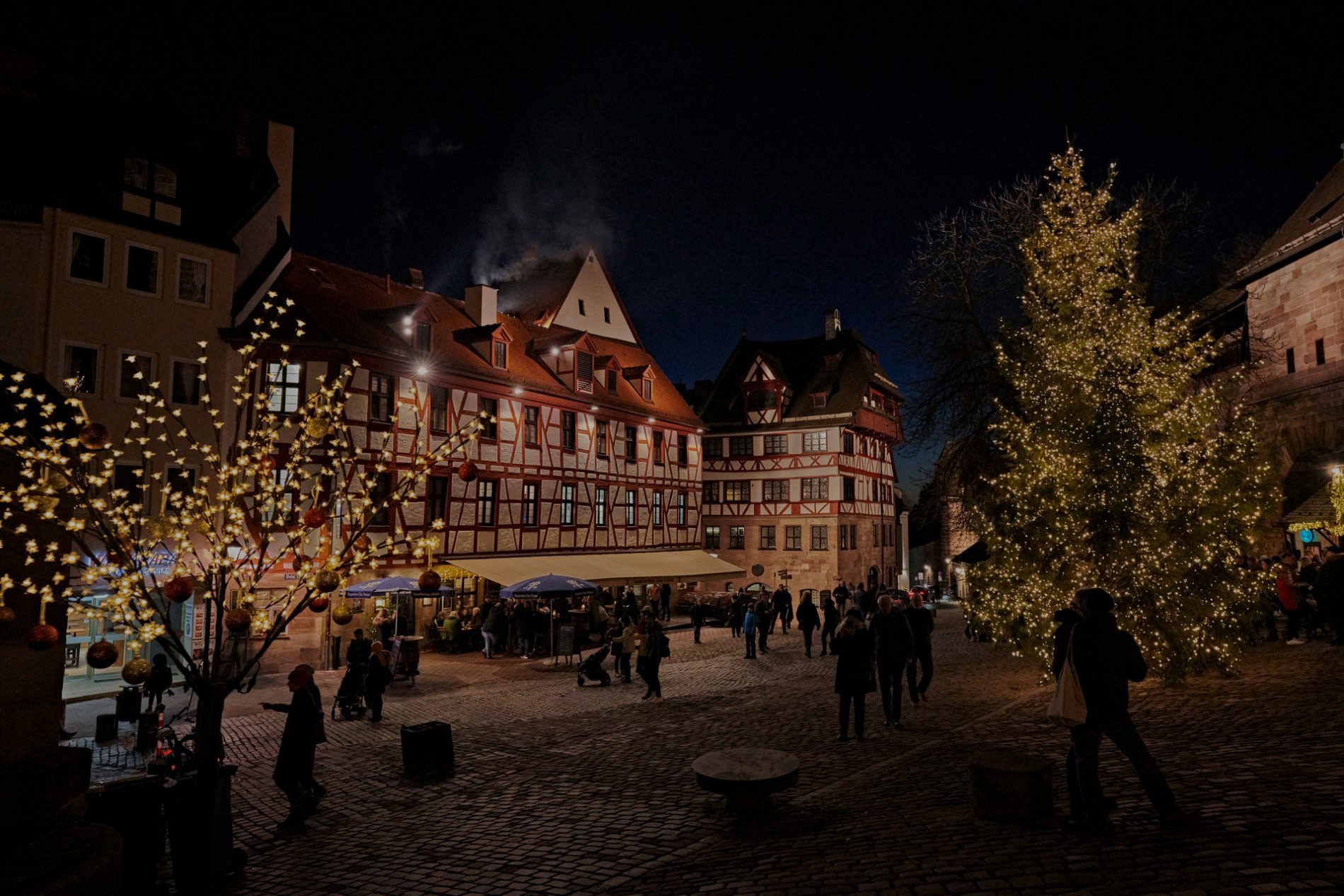 _GK15230-(c)-erlebe.bayern—Gert-Krautbauer Nachtaufnahme eines Fachwerkmarktplatzes mit beleuchteten Weihnachtsbaum und Spaziergängern.