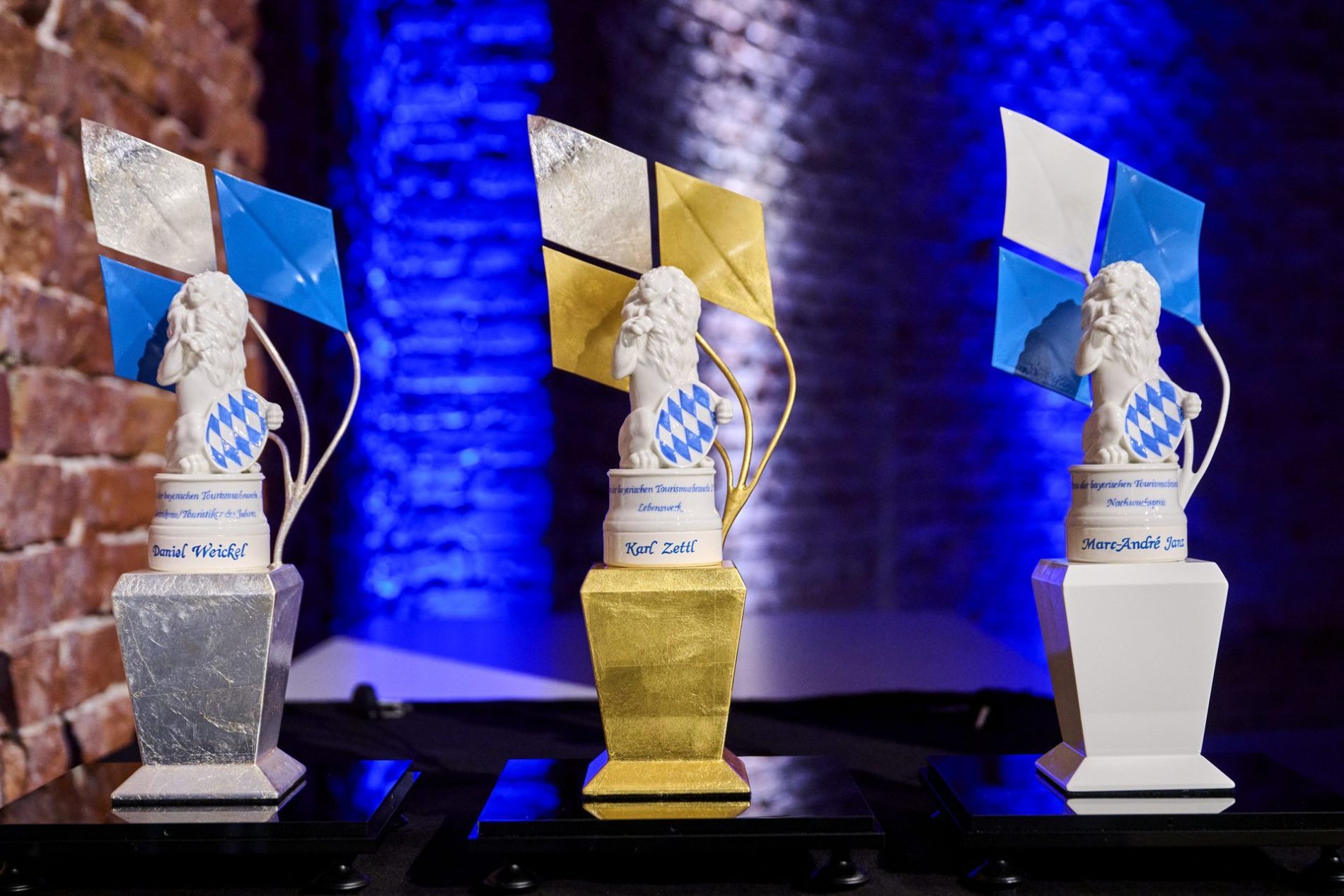 Drei Pokale in einem festlichen Umfeld, die f&uuml;r herausragende Leistungen in der bayerischen Tourismusbranche verliehen wurden.