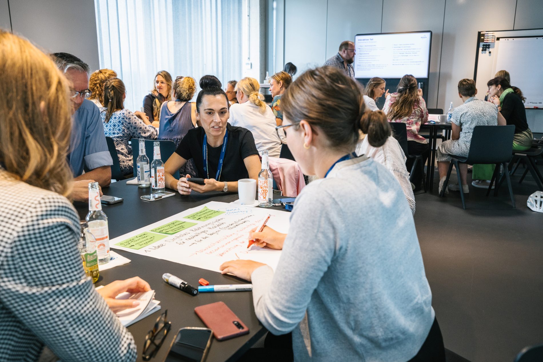 Live Netzwerktreffen Gruppe von Personen an einem Schreibtisch in Workshopatmosphäre.